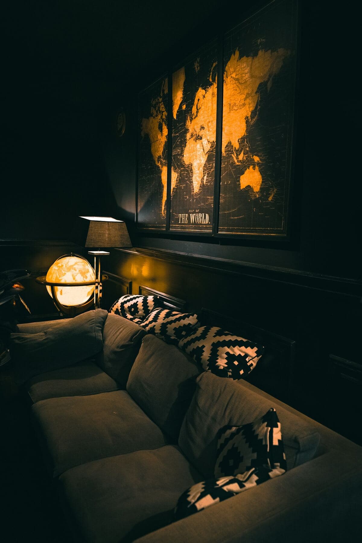 Sofa in near darkness, lit by the glow of a fireplace