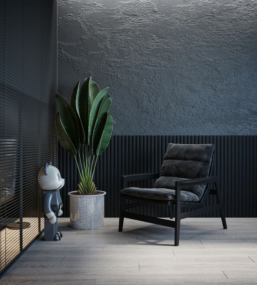 Sculpted armchair and potted plant against a textured dark wall